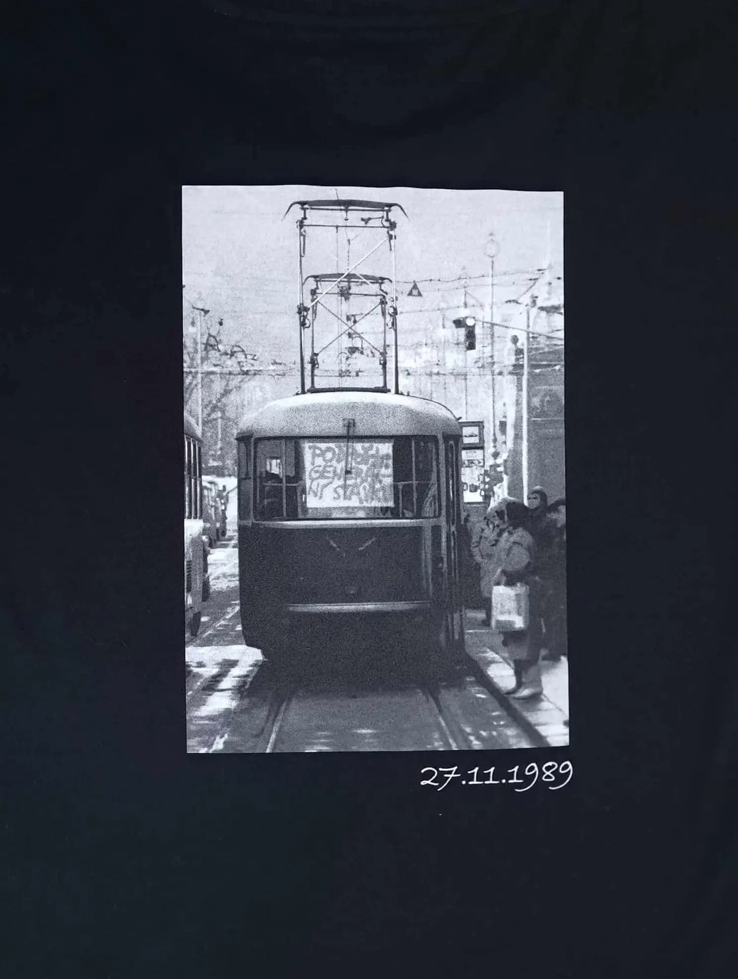Back of a black T-shirt with a black-and-white photograph of a Prague tram and the date 27 November 1989.