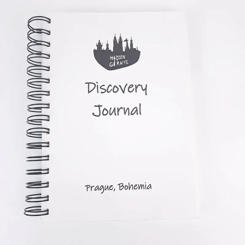 White spiral-bound Discovery Journal with the Hidden Giraffe logo and the words “Prague, Bohemia” on the cover.